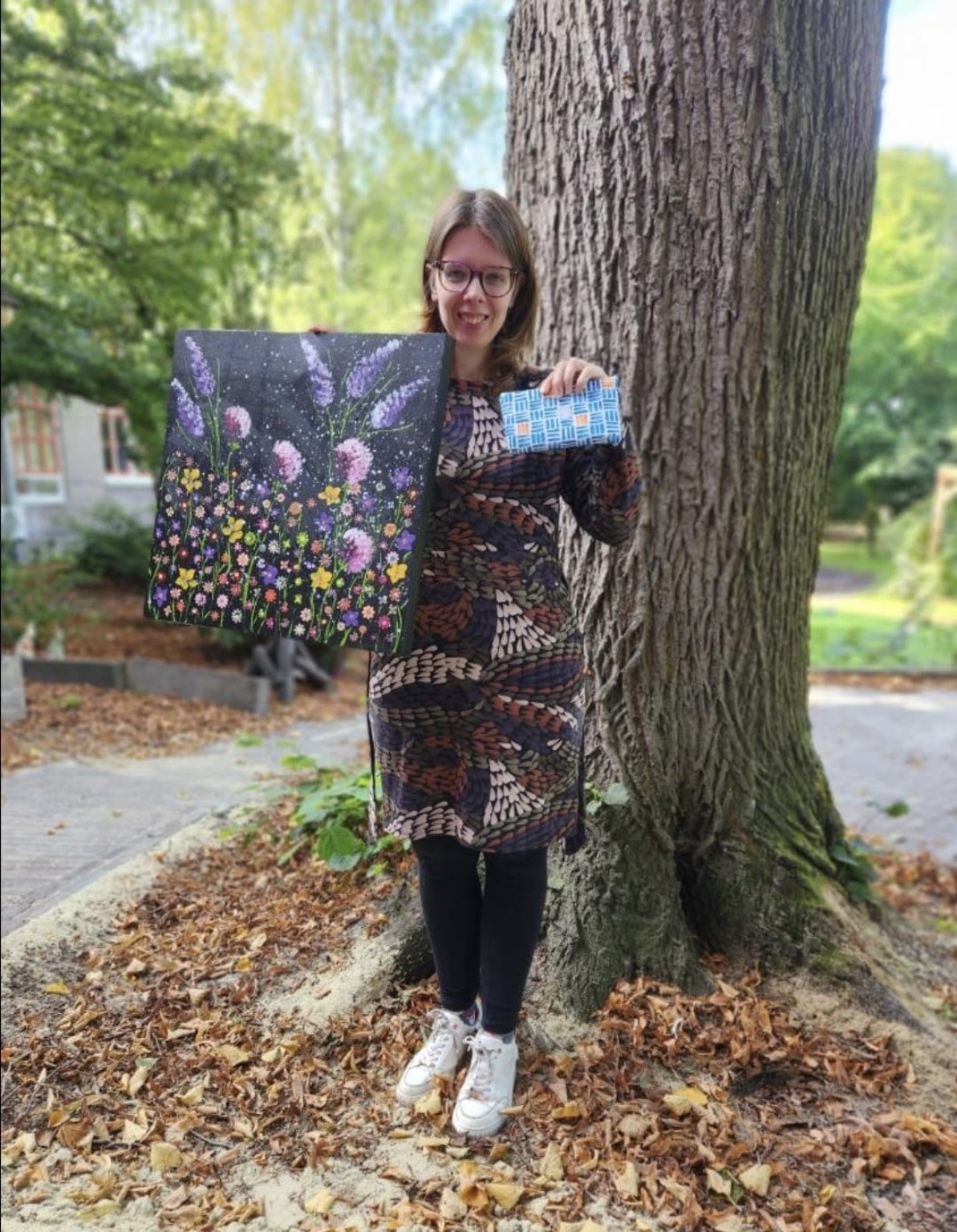 Een maker toont haar bloemenschilderij en geweven werk